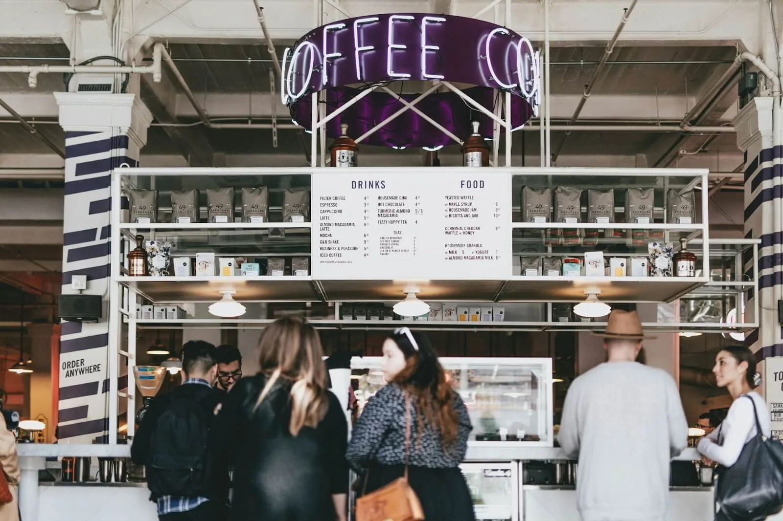 Consumers interacting with workers at a coffee stand.