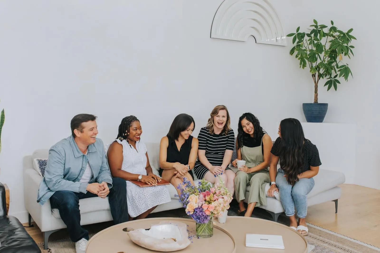 A Little Bird team sitting around a table and talking, smiling.