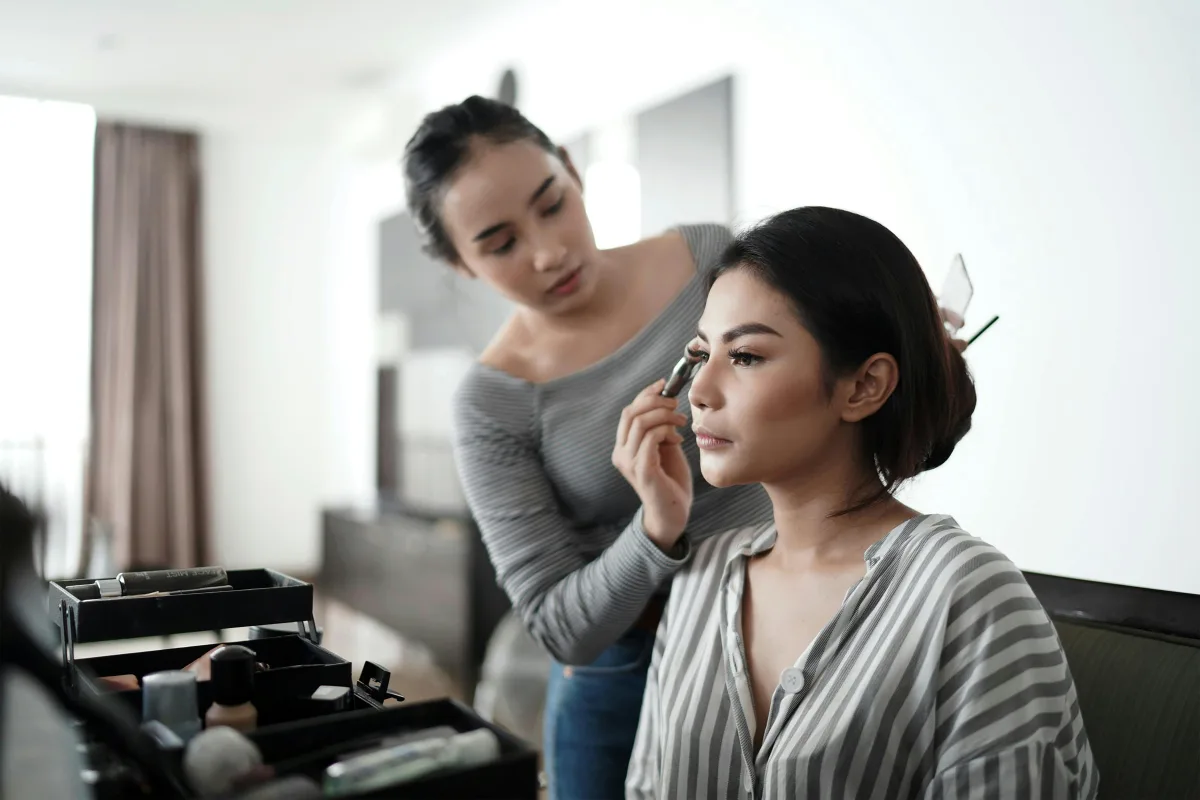A makeup artist applying eyeshadow to a client