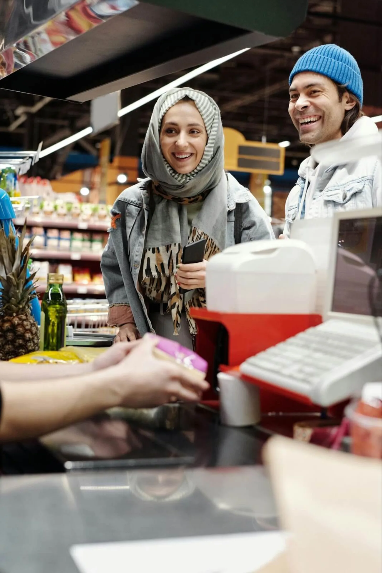 Consumers smiling while receiving something they purchased from a cashier.