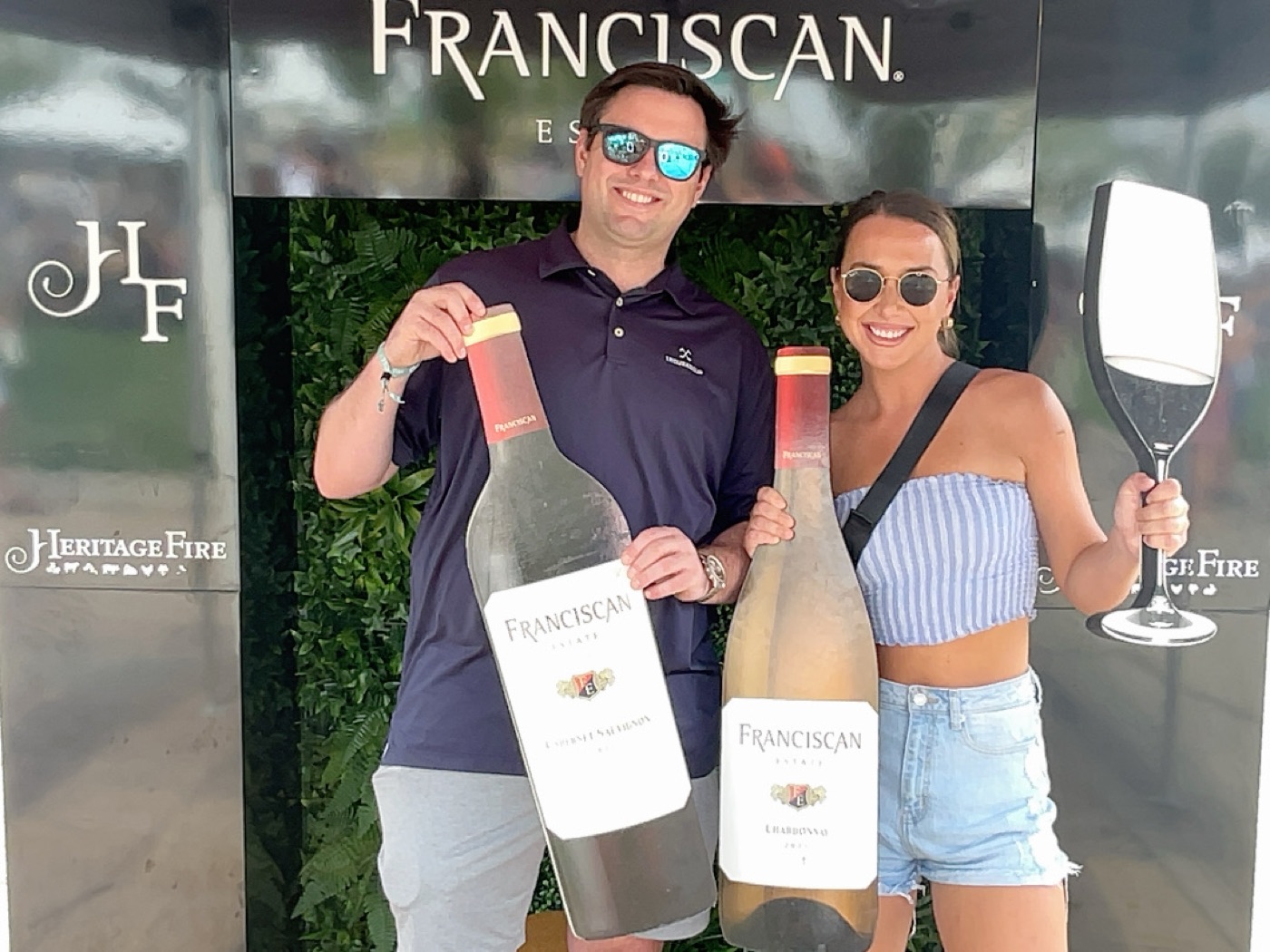Guests posing with oversized Franciscan wine bottle props at the branded Heritage Fire Festival photo moment
