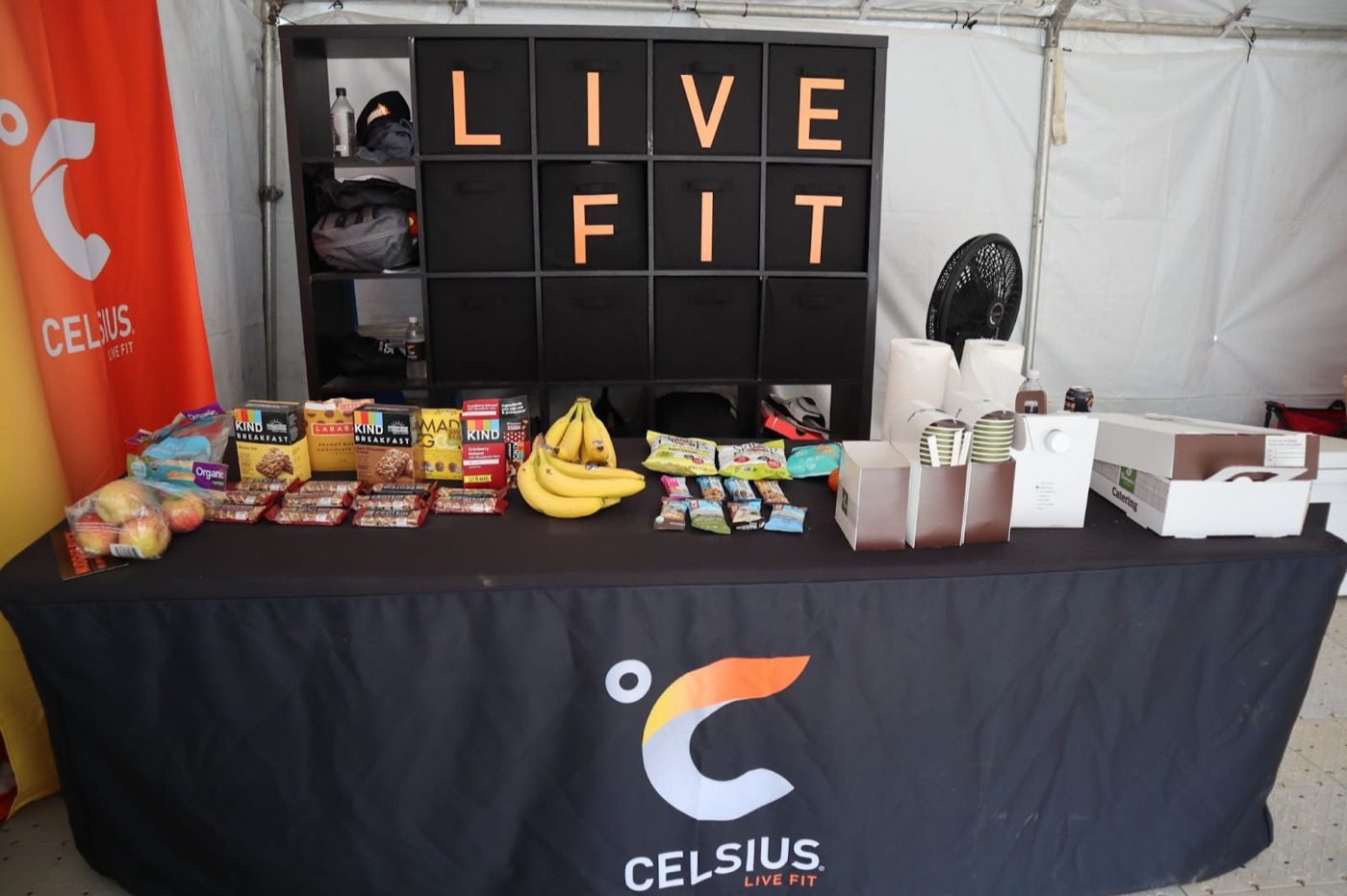 Celsius Live Fit branded sampling table with snacks and drinks set up at a fitness activation